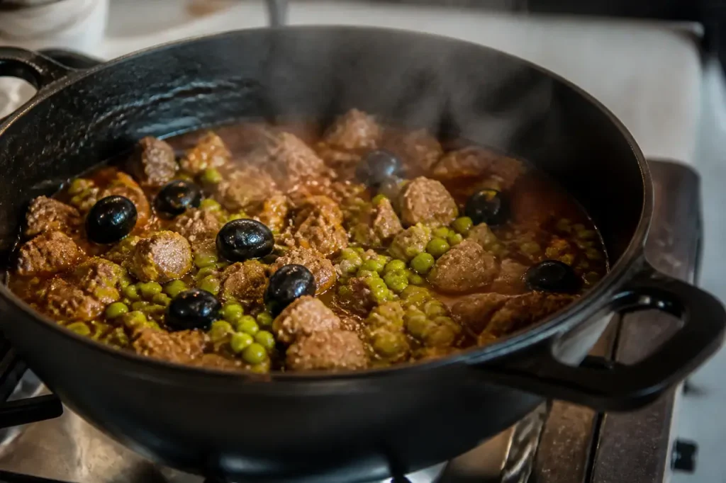 Casserole fumante de viande, olives noires et petits pois