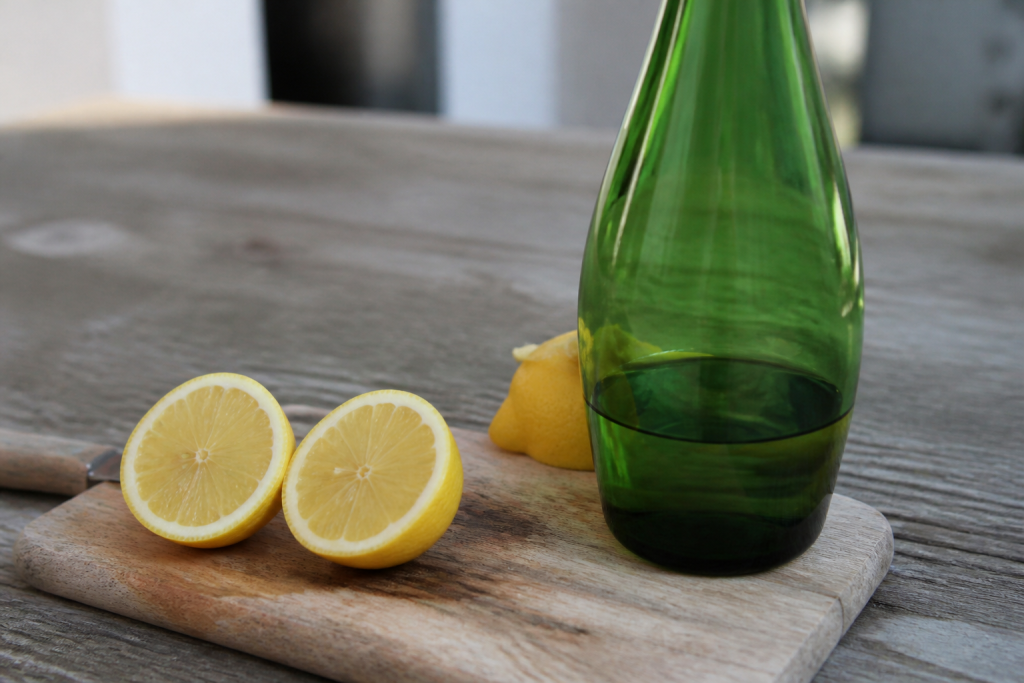 Citrons coupes et bouteille verte sur planche en bois