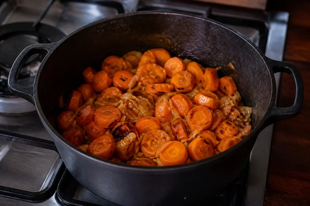 Cocotte en fonte remplie de carottes et oignons brunis