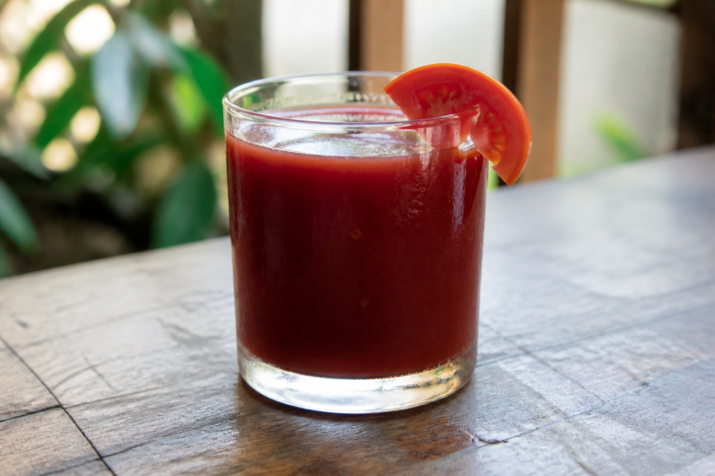 Verre rempli de boisson rouge sombre avec tomate